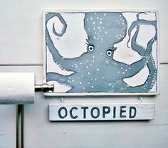 an octopus painted on the side of a white wall next to a toilet paper roll