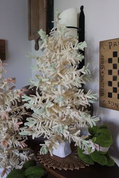 a white christmas tree sitting on top of a wooden table next to other fake trees