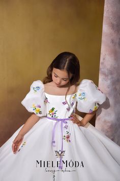 The Sunset Blossom couture flower girl dress is a true vision of elegance and charm. This exquisite gown features a fitted bodice adorned with delicate floral and whimsical butterflies embroidered appliqués and an illusion neckline that adds a touch of sophistication. The large puffy short sleeves bring a playful yet regal flair, while the full-circle, multi-layered skirt offers a graceful ballroom silhouette with options for floor or knee length. Crafted from the finest European lace, satin, and mesh fabrics, the gown is fully lined with soft fabric for maximum comfort and protection. A timeless design, complete with a zipper closure and a flowing long train, perfect for any special occasion. FEATURES: Fitted bodice accented with floral embroidered appliqués Illusion neckline Floor or kne Lavender Ribbon, Exquisite Gowns, Corset Style Tops, Illusion Neckline, Floor Length Gown, Flowing Skirt, Floral White, Summer Events, Flower Girl Dress