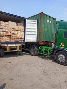 two green trucks are parked next to each other in the dirt with boxes on them