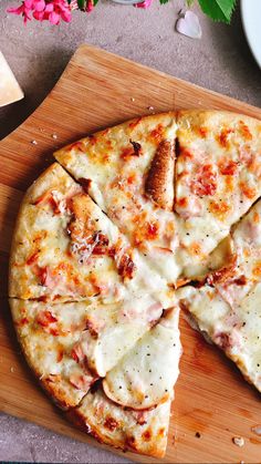 a sliced pizza sitting on top of a wooden cutting board