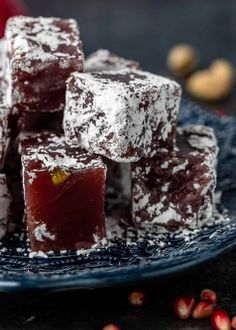 a blue plate topped with pieces of chocolate covered in powdered sugar and surrounded by pomegranates