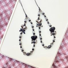 a pair of black and white heart shaped beads on a table with gingham cloth