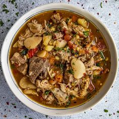 a white bowl filled with meat and vegetable soup on top of a blue table cloth