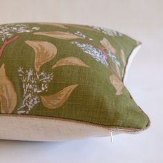 a close up of a pillow on a white surface with green and yellow floral designs