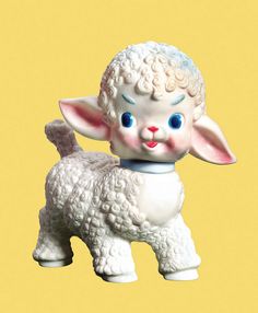 a white sheep figurine with blue eyes on a yellow background