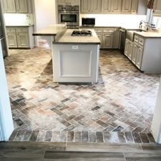 a kitchen with an island in the middle and tile flooring on the other side