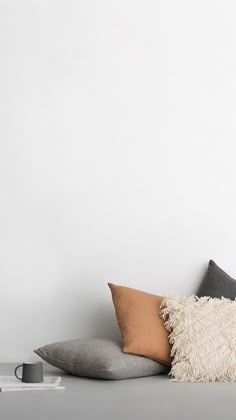 a white couch with some pillows on top of it and a coffee cup next to it