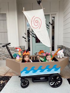 two children in a cardboard boat on the front porch