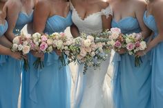 a group of bridesmaids in blue dresses holding bouquets with pink and white flowers