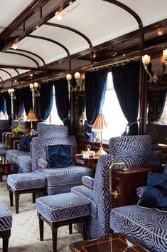 the interior of a train car with blue and white striped chairs, lamps, and windows