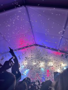 confetti falling from the ceiling at a party with people in the back ground