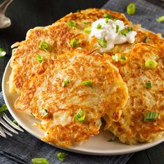 two pancakes on a plate with sour cream and scallions in the middle, ready to be eaten