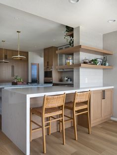 two wooden chairs sitting on top of a kitchen counter next to an island with built - in shelves