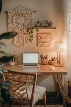 a laptop computer sitting on top of a wooden desk next to a lamp and potted plant