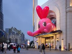 an inflatable pink elephant is on display at the entrance to a shopping mall