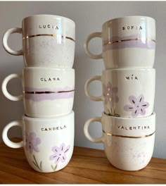 four white coffee cups stacked on top of each other with purple flowers painted on them