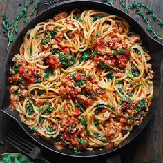 a skillet filled with spaghetti and meat covered in marinara sauce, parsley