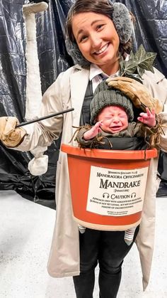 a woman holding a bucket with a baby in it