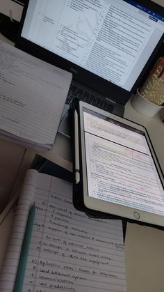 an open laptop computer sitting on top of a desk next to a notebook and pen