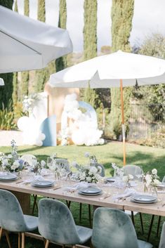 an outdoor table set up with white flowers and place settings