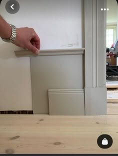 a hand is holding the door handle on an unfinished piece of wood that has been painted white