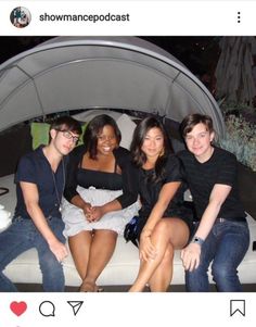 four people are sitting on a white bench