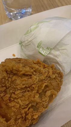 a fried food item on a white plate with a glass of water in the background