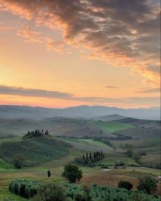 the sun is setting over rolling hills and fields