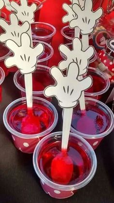 some cups with red liquid in them and mickey mouse stickers on the top one