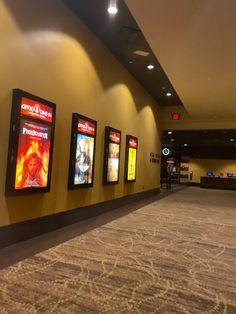 an empty lobby with posters on the wall and carpeted flooring in front of it