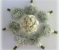 a bouquet of white roses and baby's breath flowers arranged in a circular arrangement