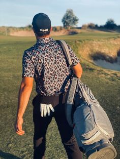 a man with a back pack walking towards the golf course on a sunny day,