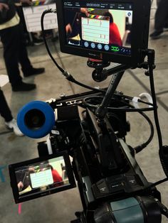 a video camera on a tripod with people in the background