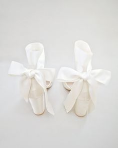 two pairs of white shoes with bows on them