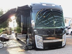 a large black bus parked on the side of a road next to a small child's carriage