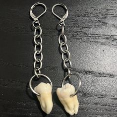 a pair of white teeth dangling from silver chains