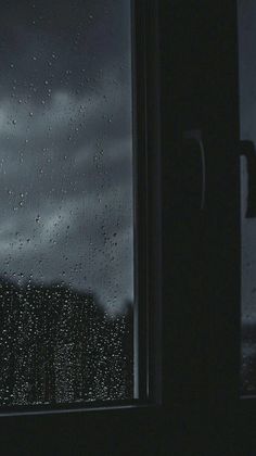 a window with rain drops on it and the sky in the background