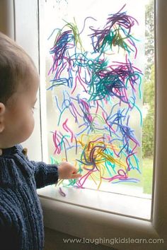 a little boy is looking out the window at something in the air that has been drawn on it