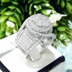 a diamond ring sitting on top of a white box next to some flowers and greenery