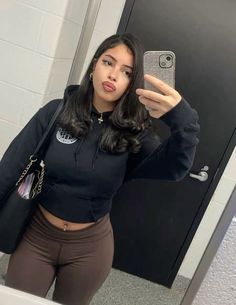 a young woman taking a selfie in front of a mirror with her cell phone