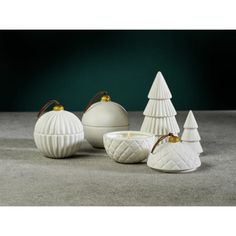 three white ceramic christmas trees, one with a candle holder and the other with a bowl