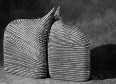 black and white photograph of two vases sitting side by side on the ground in front of a wall