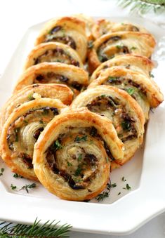 a white plate topped with pastry rolls covered in cheese and herbs on top of it