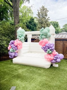 an inflatable chair with balloons attached to it on the grass near a tree