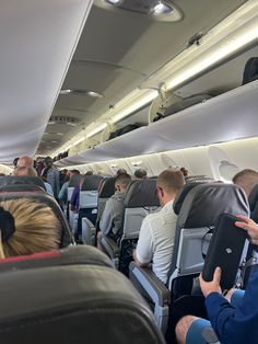 people sitting in seats on an airplane with their backs turned to the side as they look at something