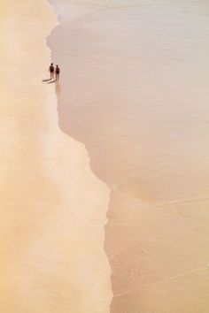 two people are walking along the beach together