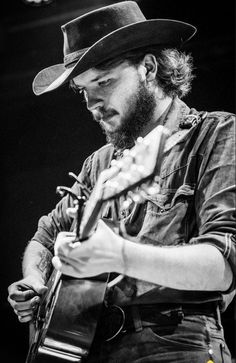 a man with a hat playing an acoustic guitar