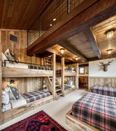 there are two bunk beds in the room with plaid blankets on them and a rug