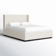 a bed with white sheets and pillows on it